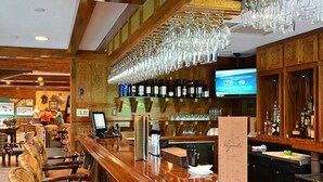 Eine Bar mit Holzzimmereinrichtung, einer Theke und einem Fernsehbildschirm.