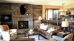 Ein gemütliches Wohnzimmer mit Kamin aus Stein, einer bequemen Couch und einem Fernseher.