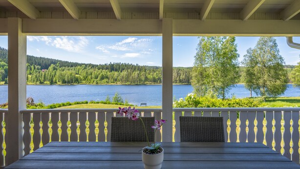 A covered outdoor seating area with a view of a lake and forest.