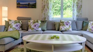 A living room with a sofa, pillows, a table, and a window with curtains.