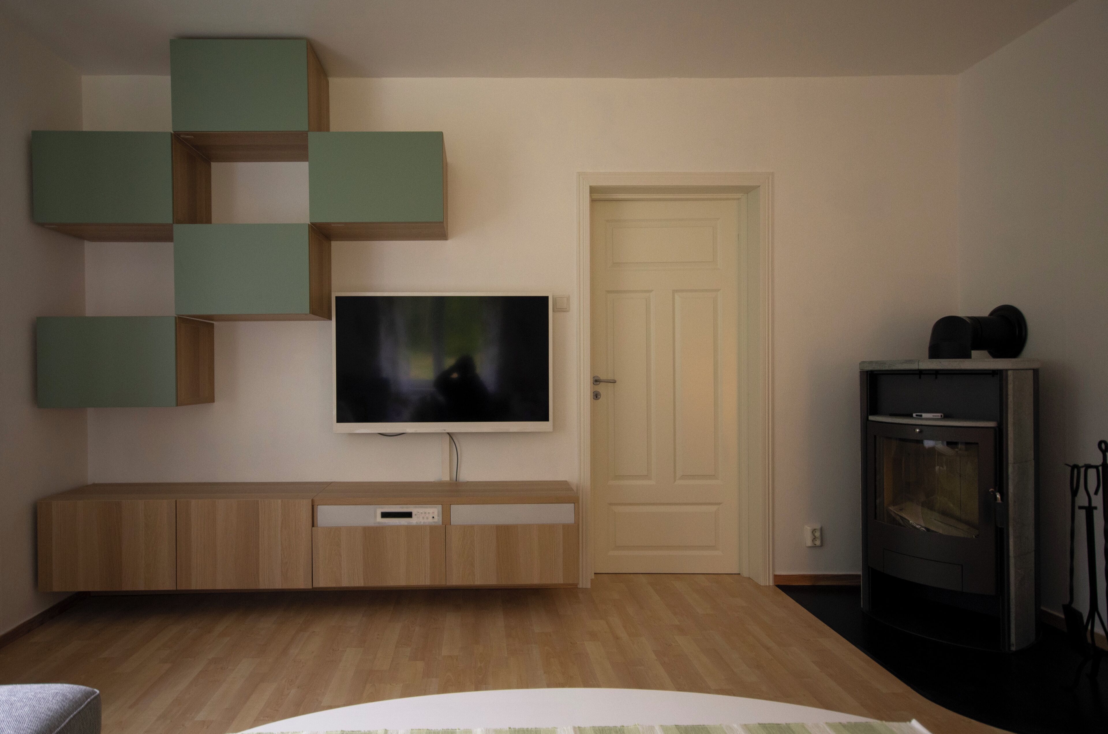 Een moderne woonkamer met een flatscreen televisie, bevestigd aan een houten kast, een open haard en een deur.