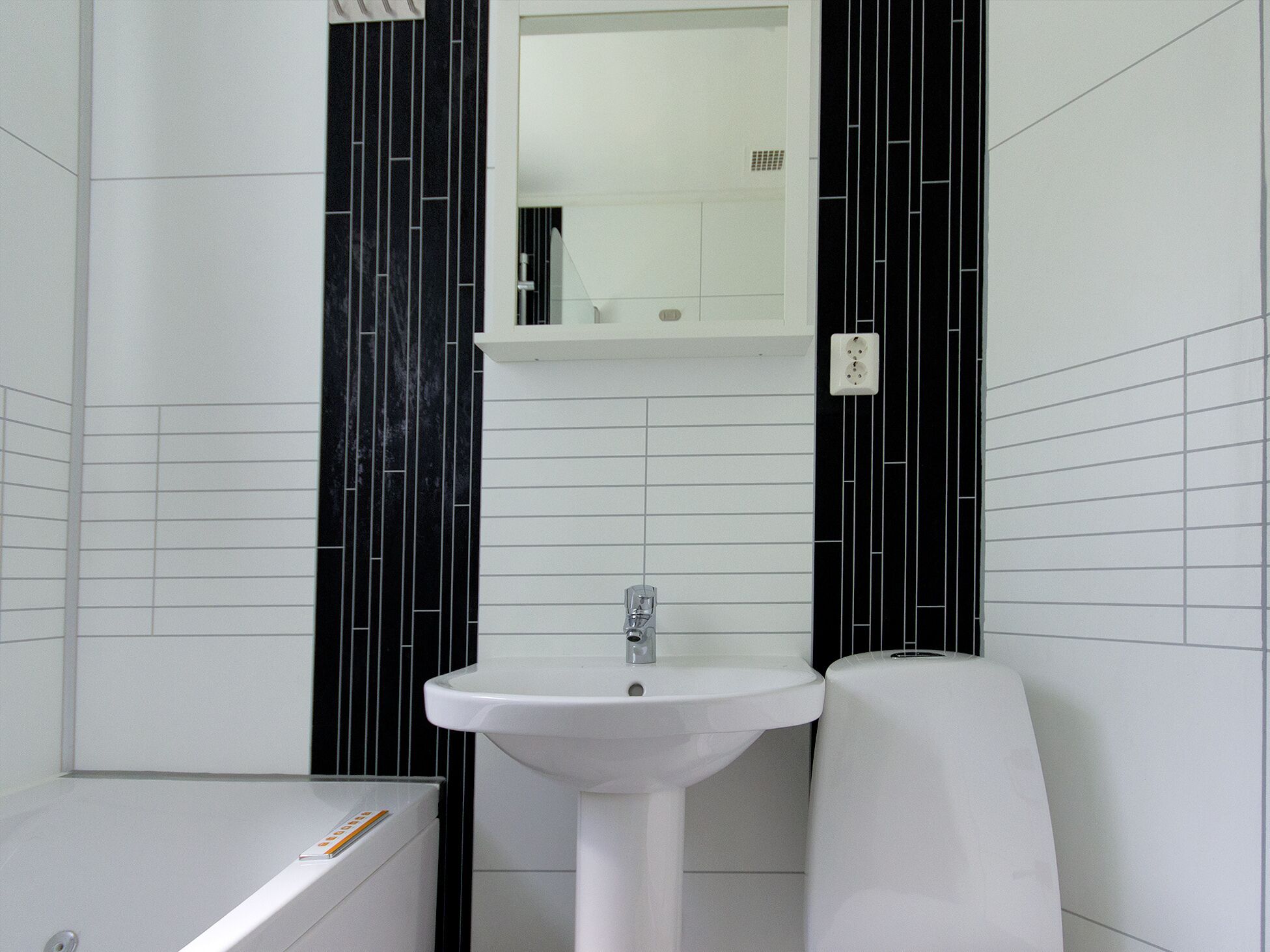 A bathroom with a white sink, a mirror above it, and black vertical stripes on the walls.