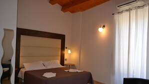 A hotel room with a large bed, a small bedside table, a chair, and a window with curtains. - MAESTRALE 1 bedroom apt 2/4 sleeps  with Pool - Modica - Sicily (MODICA)