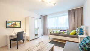 Una sala de estar moderna con un sofá, un televisor, un escritorio y una ventana con cortinas.