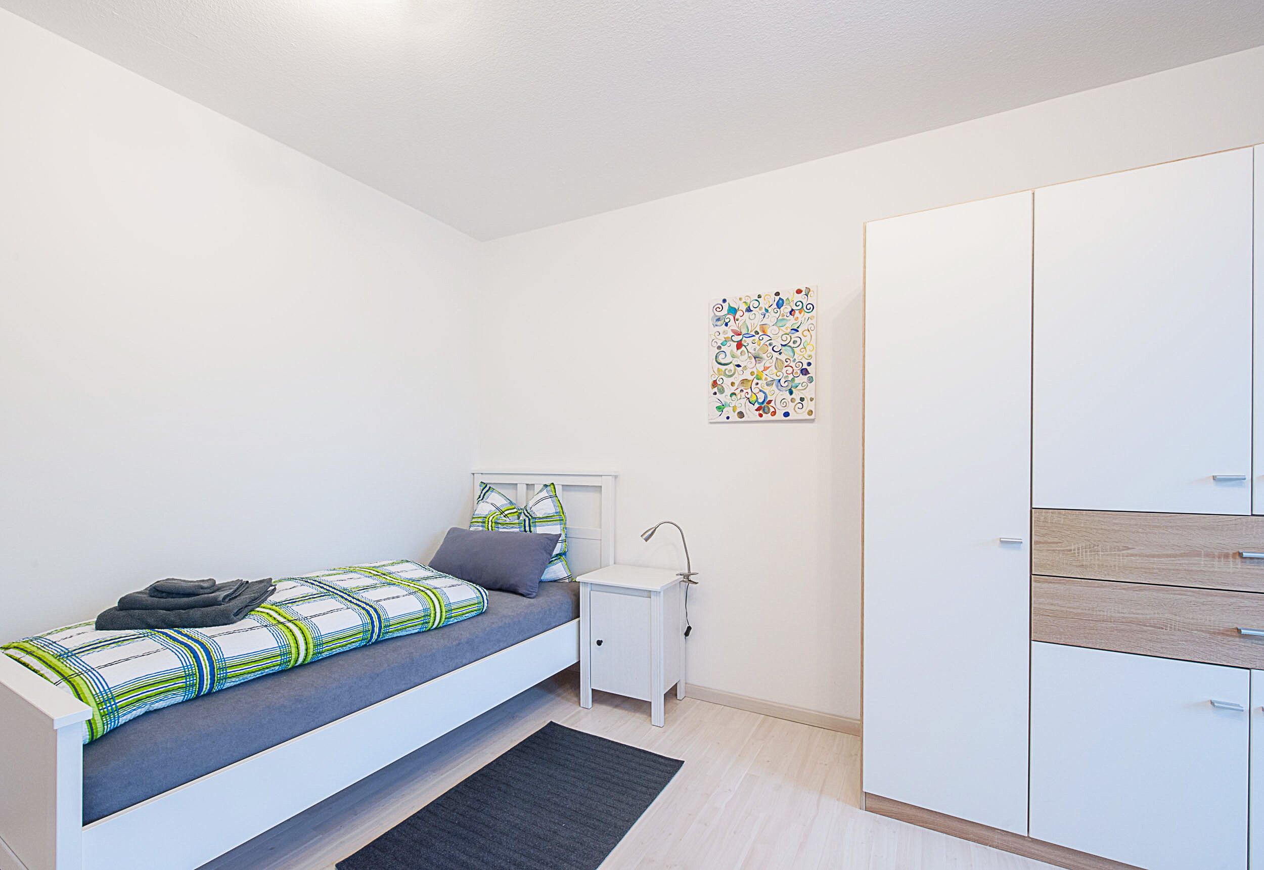 A bedroom with a bed, bedside table, and wardrobe.