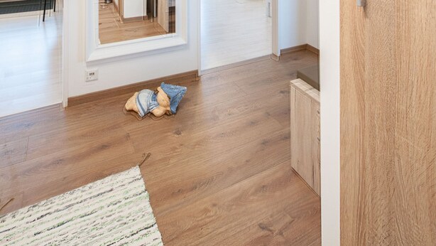 Un apartamento moderno con piso de madera, un área de comedor y una cocina visible a través de una puerta abierta.