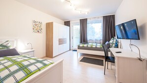 Un dormitorio moderno con cama, escritorio y televisión.