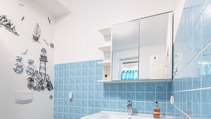 Un baño con un lavamanos blanco, azulejos azules y suelo de madera.