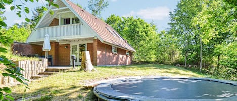 A house with a porch, a trampoline, and a brick exterior.