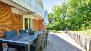 An outdoor patio with a table and chairs, a covered area, and a brick wall.