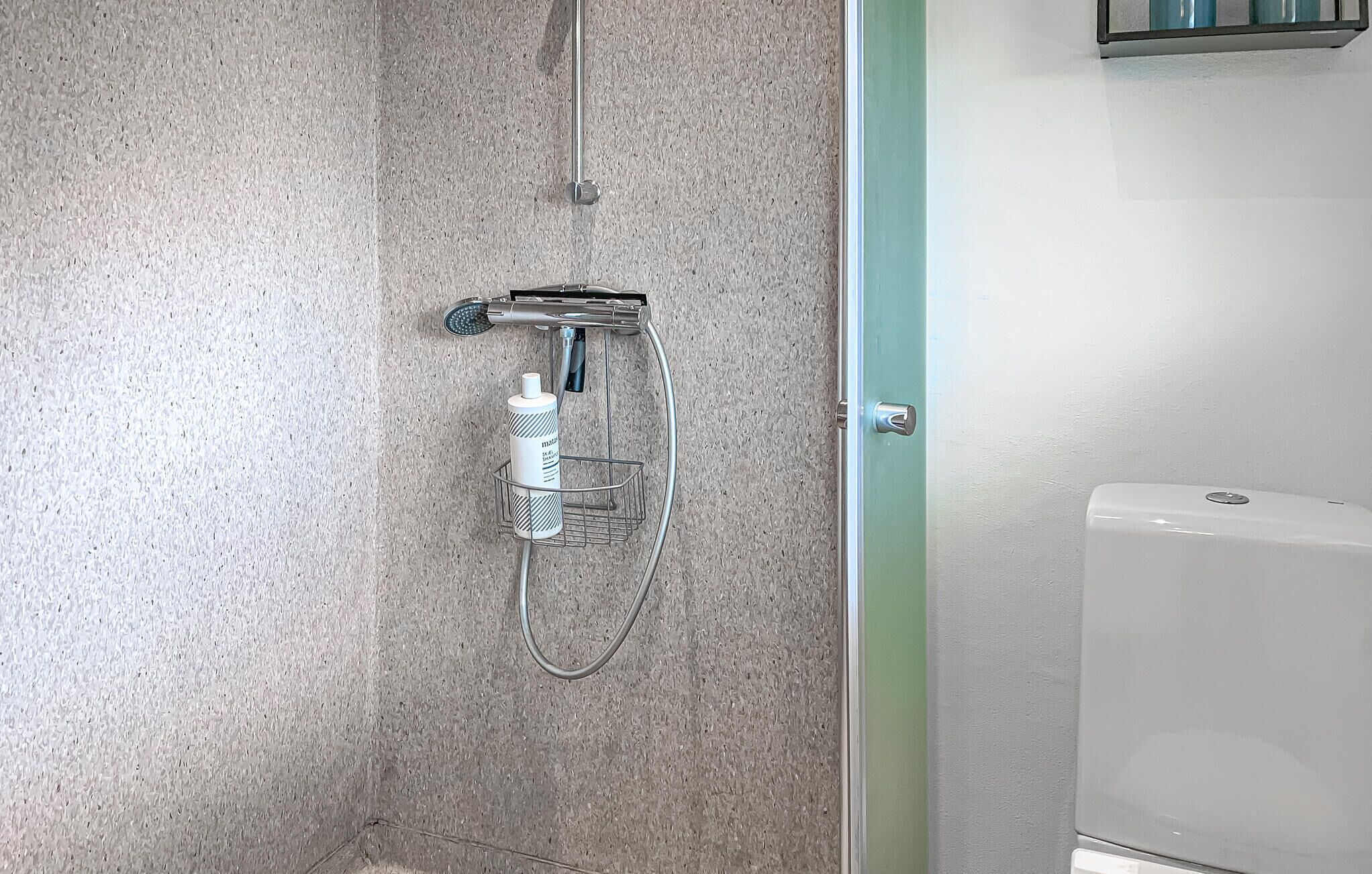 Un baño con ducha, inodoro y toallero.