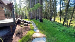 A wooden cabin with a stone pathway leading to a deck. - Stillwater River Escape, Amazing Views, Secluded! (Whitefish)