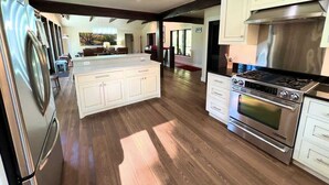 A spacious kitchen with a central island, stainless steel appliances, and white cabinetry. - Stillwater River Escape, Amazing Views, Secluded! (Whitefish)