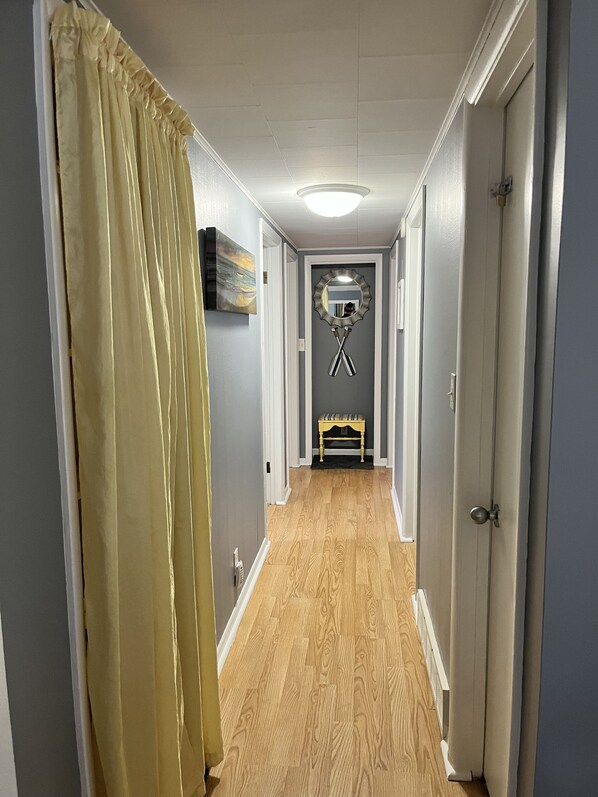 A hallway with wooden flooring, a bench, a mirror, and a door.
