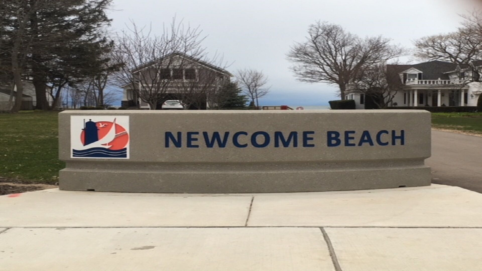 Schild für Newcombe Beach mit einem Logo mit Segelboot und Wellen.