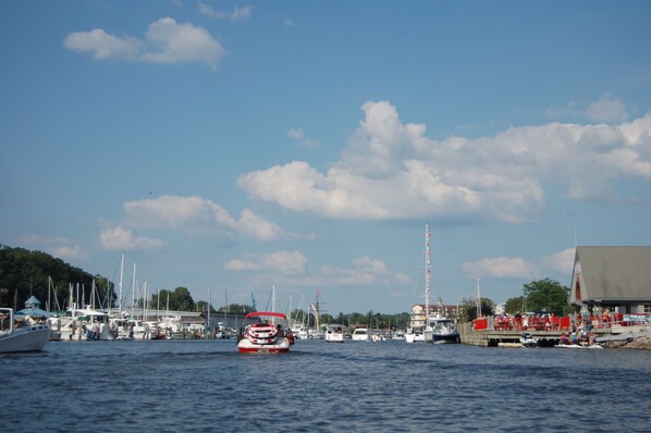 A marina with boats docked, a small boat in the foreground, and a building with outdoor seating on the right.
