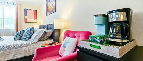 Ein Hotelzimmer mit einem Bett, einem roten Sessel, einer Kaffeemaschine und einer Packung Green Mountain Dark Magic Kaffee.