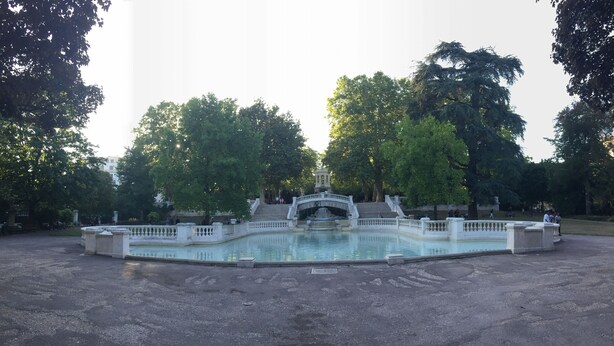 Une grande piscine rectangulaire dotée d’une fontaine centrale et d’un pont.