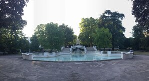 Une grande piscine rectangulaire dotée d’une fontaine centrale et d’un pont.