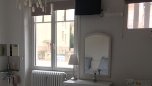 Une chambre avec deux lits, une commode, un miroir, un radiateur et un téléviseur fixé au mur.