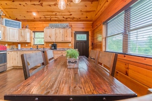 A wooden cabin interior with a dining table, chairs, a coffee station, and a sign reading "FRESH EGGS". - True Log Cabin, Hot tub, Fire Pit, Easy access and close to downtown. (Gatlinburg)