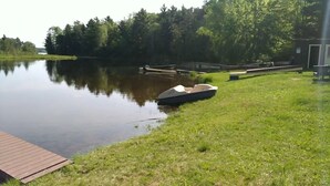 A calm lake with a boat dock, grassy banks, and a wooden deck.