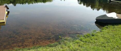 Un lago tranquilo con un muelle y un bote pequeño.