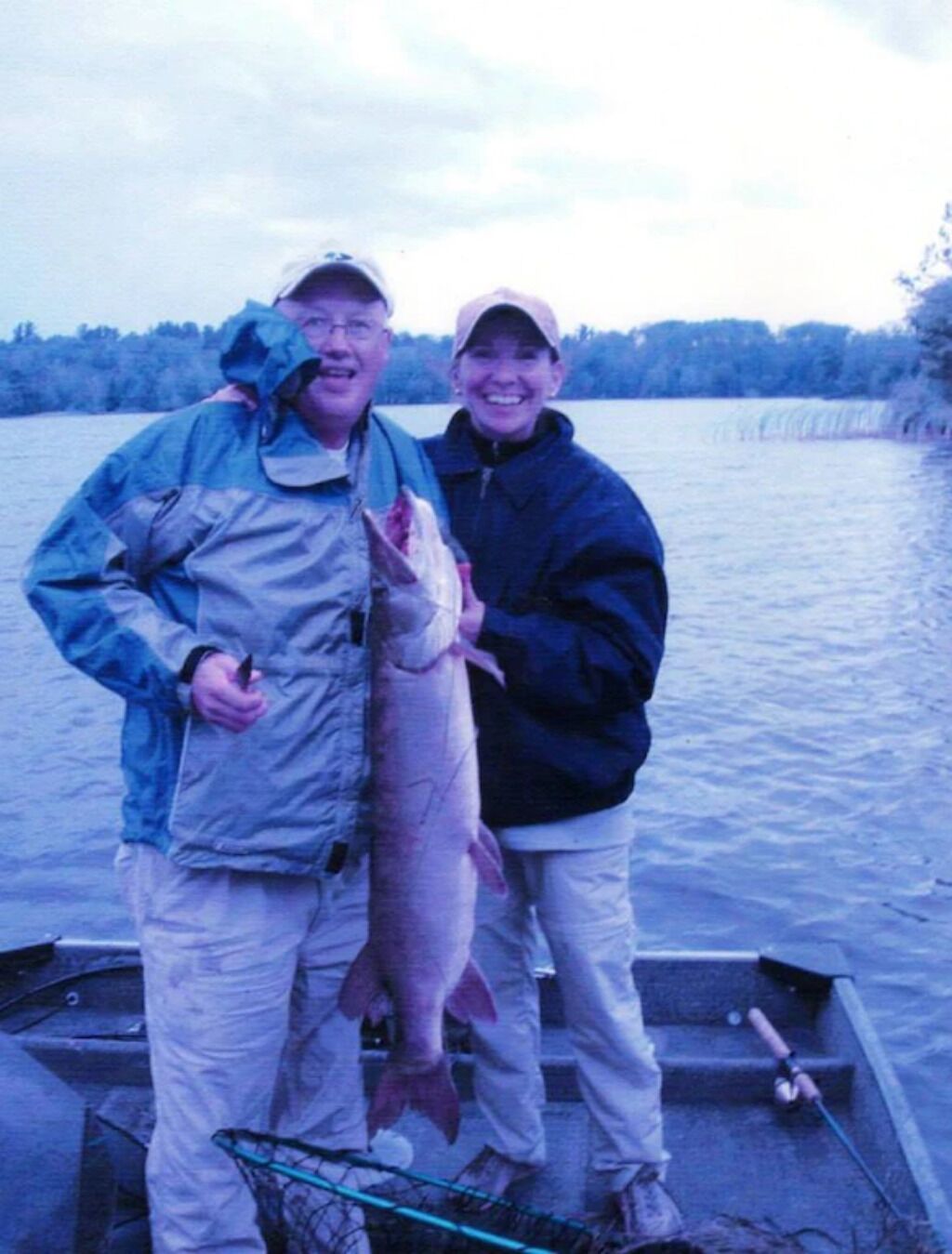 Zwei Personen in einem Boot halten einen großen Fisch.