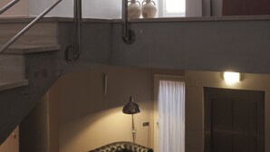 Ein mehrgeschossiges Interieur mit Treppe, Sofa, Lampe und Tür.