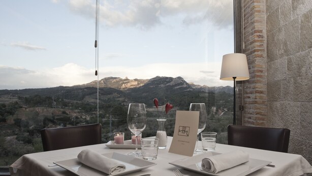 Ein Tisch für zwei Personen mit Blick auf die Berge, eine Lampe und eine Speisekarte.