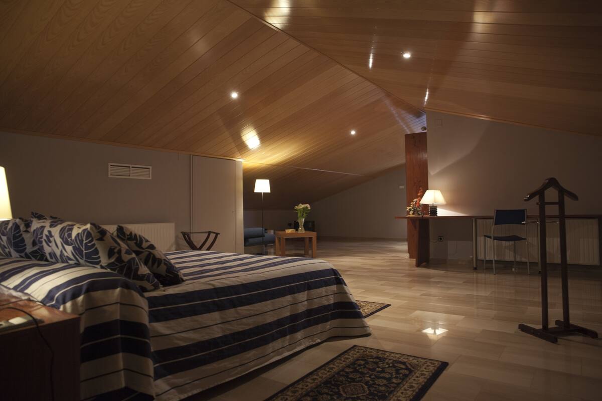 A bedroom with a bed, a desk, and a chair.