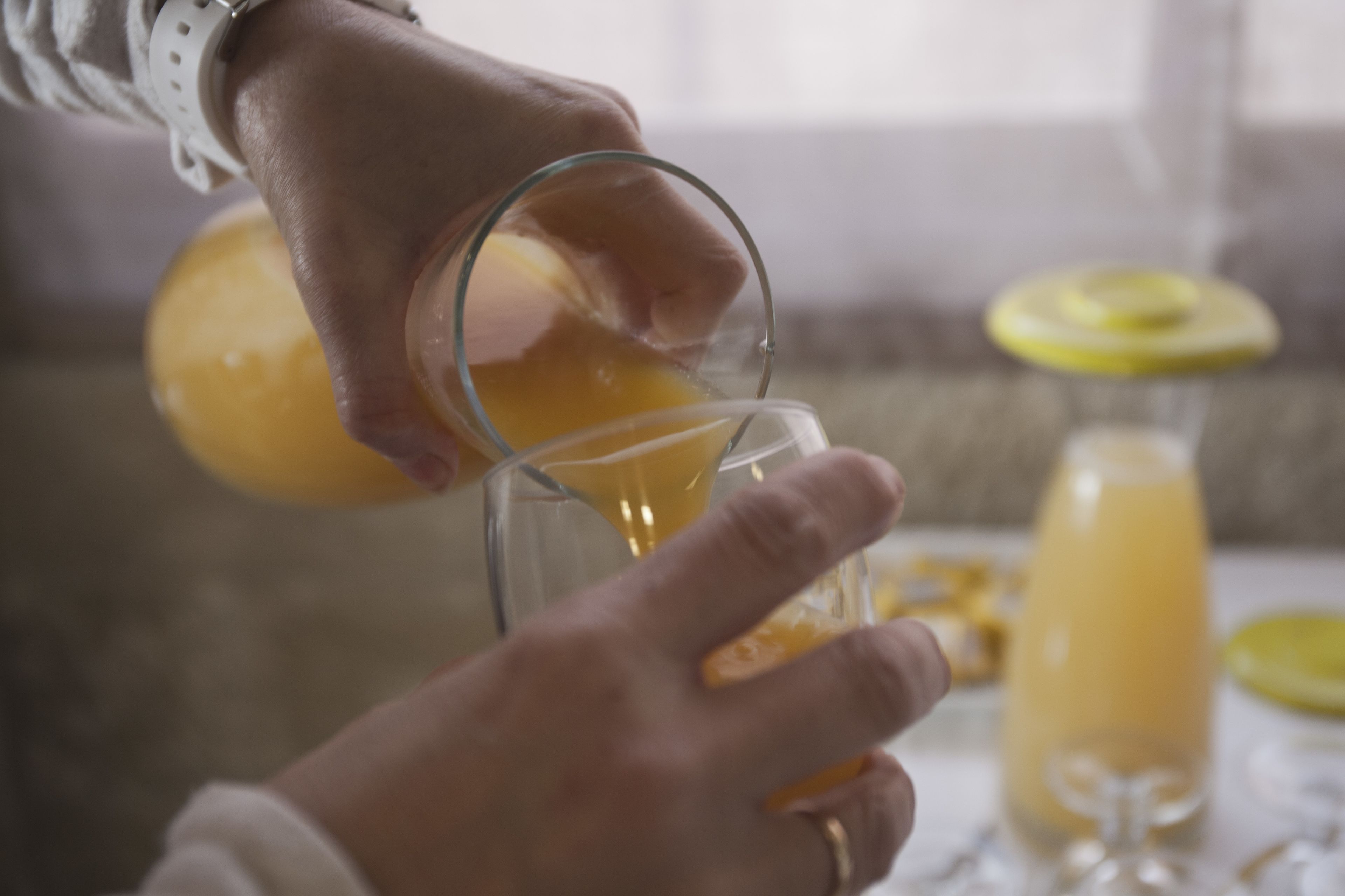 Una persona vertiendo un líquido amarillo en un vaso.