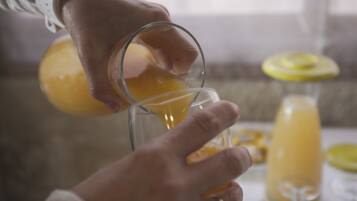 Una persona vertiendo un líquido amarillo en un vaso.