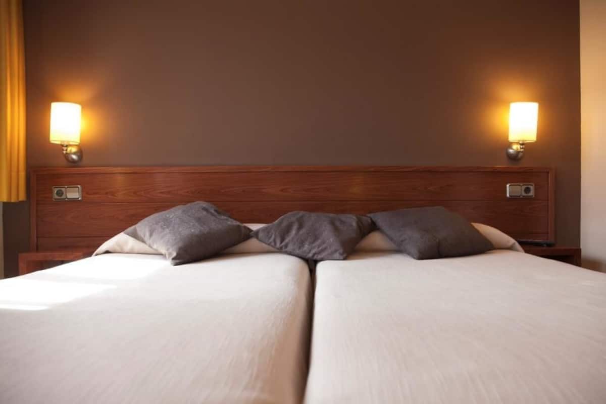 A double bed with a wooden headboard, two bedside lamps, and a neutral color scheme.
