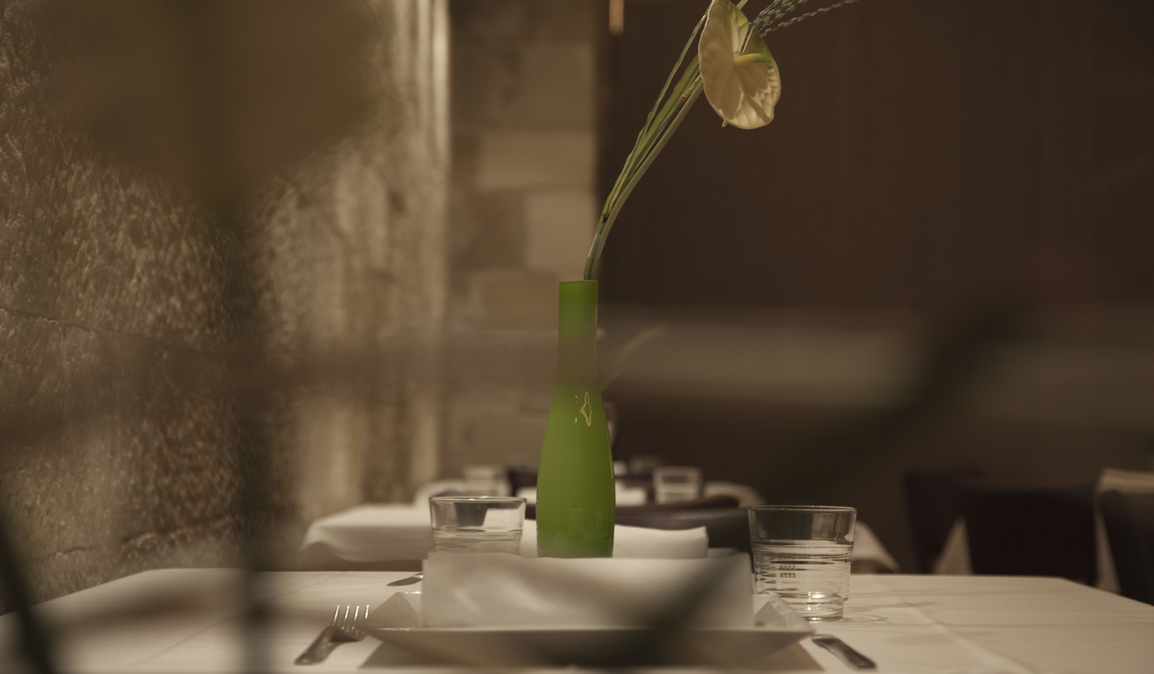 A dining table with a vase, a glass, and a plate.