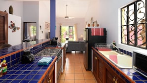 Een keuken met blauw betegelde aanrechtbladen, een koelkast, een fornuis en een spoelbak.