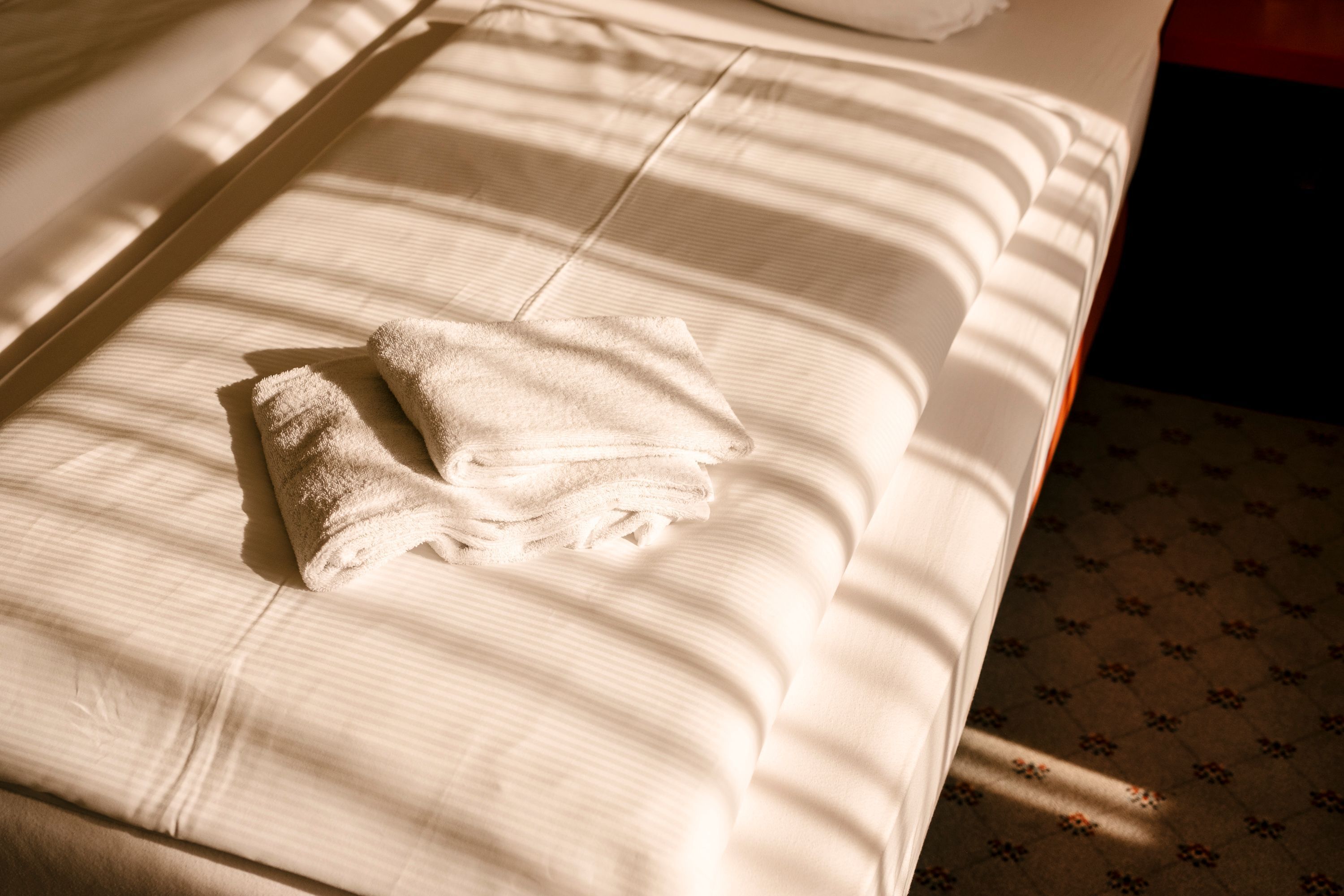 A neatly made bed with a folded white towel on the bed.