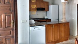 Una cocina con armarios de madera, un lavavajillas blanco y un refrigerador blanco.