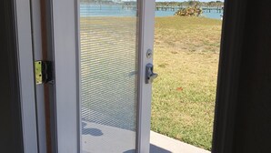A door with a view of a grassy area and a body of water. - Private Beach Front Cottage- unit 1 (Fort Pierce)
