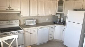 A kitchen with white cabinets, a microwave, a stove, a dishwasher, and a refrigerator. - Private Beach Front Cottage- unit 1 (Fort Pierce)