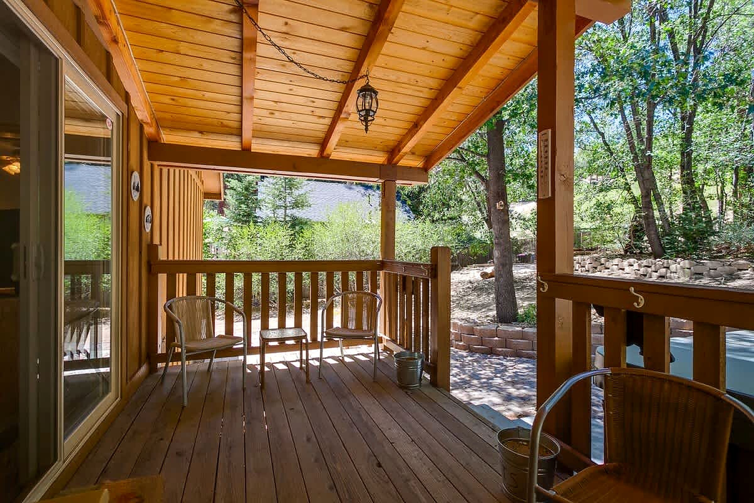 A wooden deck with two chairs and a table, overlooking a natural landscape.