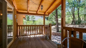 A wooden deck with two chairs and a table, overlooking a natural landscape.