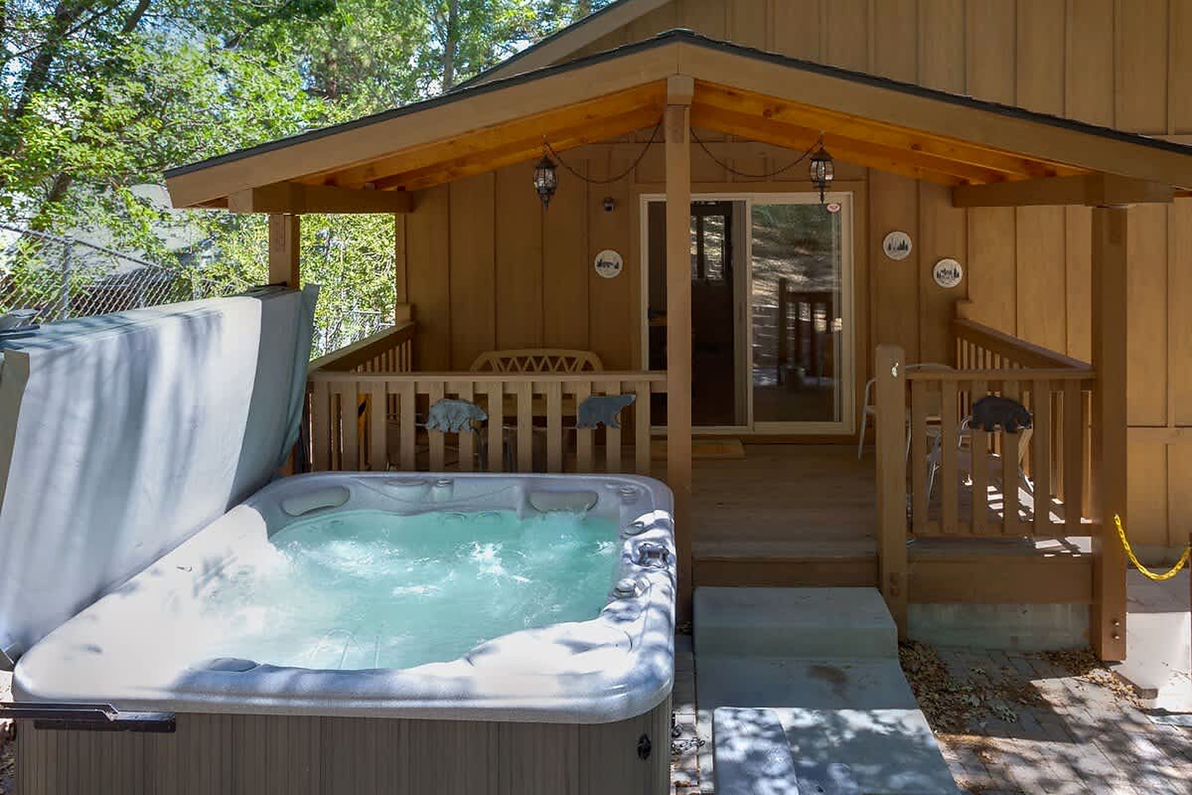 Une cabane en bois dotée d’un bain à remous, d’une véranda et d’une porte donnant sur l’intérieur.