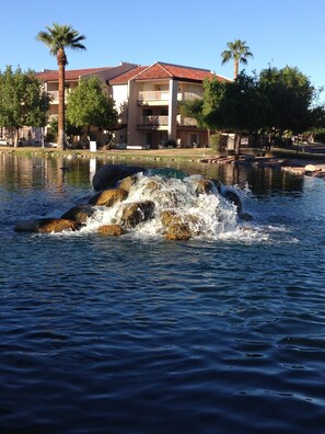 A water feature with rocks in a pool, surrounded by a building with a red roof and balconies. - LAKEFRONT-BEAUTIFUL, PEACEFUL VIEWS-HEATED POOl & JACUZZI (Phoenix)