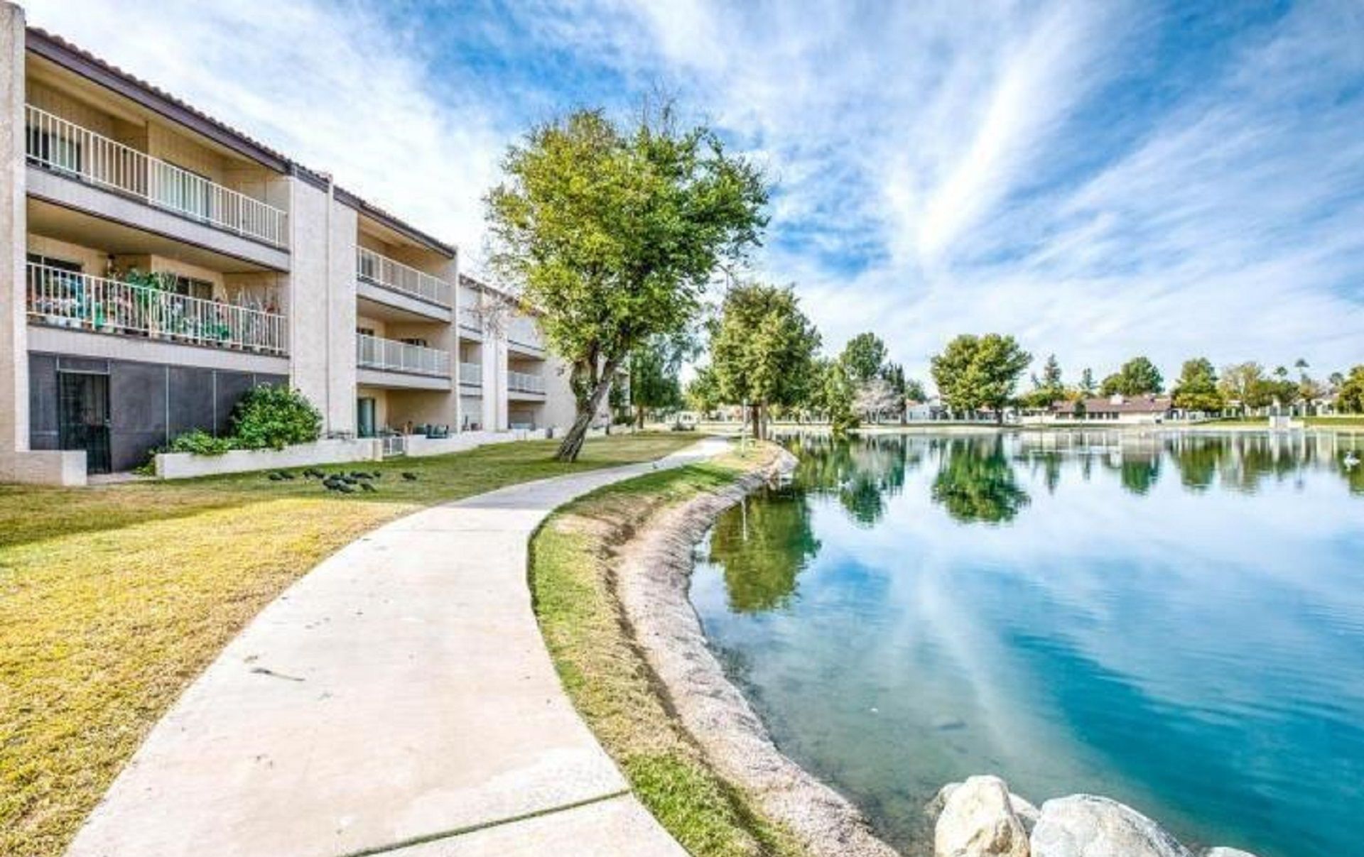A modern building with a pool, a clear sky, and a calm water body.