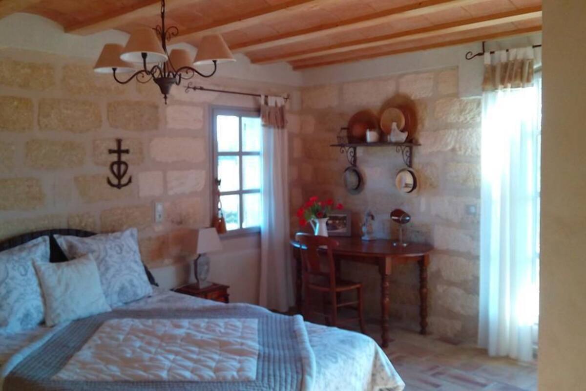 A bedroom with a bed, a desk, and a window.