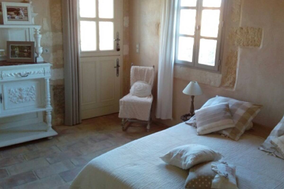 A bedroom with a bed, a chair, a dresser, and a window.
