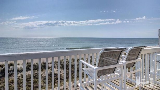 A beach view with a white railing and two beach chairs. - Oceanfront Condo with Fantastic Views (Kure Beach)