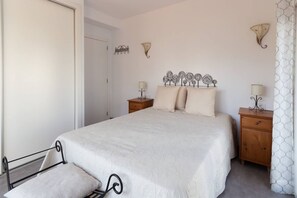 A bedroom with a bed, bedside tables, and decorative wall sconces.