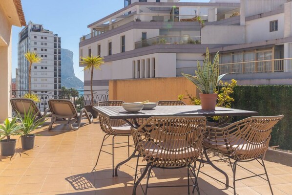 A terrace with a table and chairs, surrounded by potted plants.